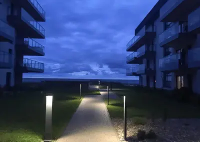 Beleuchteter Gehweg der Appartementanlage in Dziwnów bei Nacht mit modernem Gehweg und Blick Richtung Ostsee.