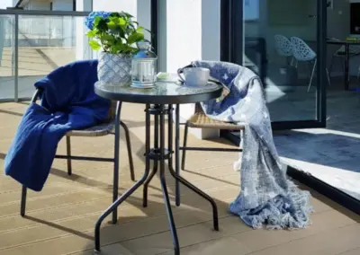 Gemütlicher Balkon des Ferienappartements in Dziwnów mit Tisch, Stühlen, Decken und entspannter Atmosphäre im Freien.