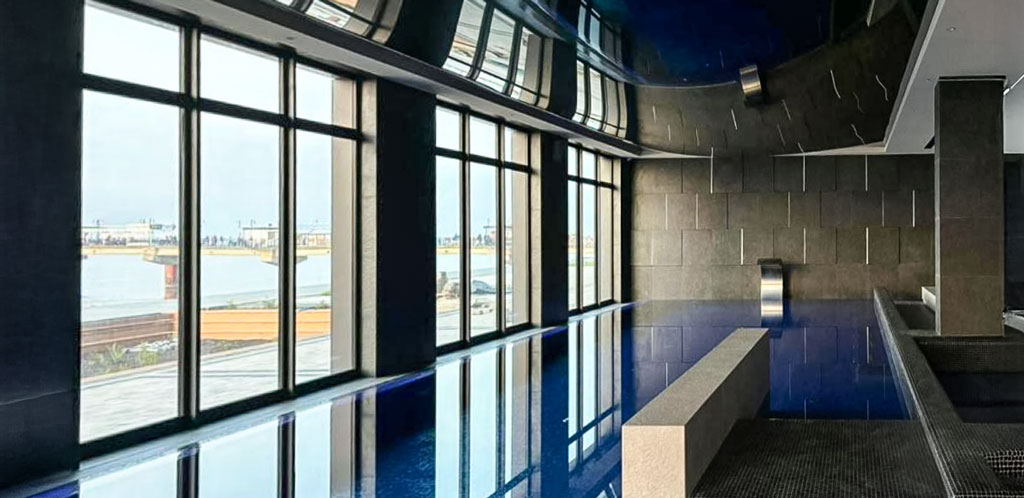 Ogrzewany basen z widokiem na Morze Bałtyckie Kryty basen w strefie wellness kompleksu apartamentowego w Międzyzdroje z panoramicznymi oknami i widokiem na Morze Bałtyckie i molo.