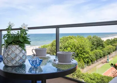 Balkon im Ferienappartement Dziwnów mit Kaffeetisch, Meerblick auf die Ostsee und Blick über Strand und Tennisplatz.