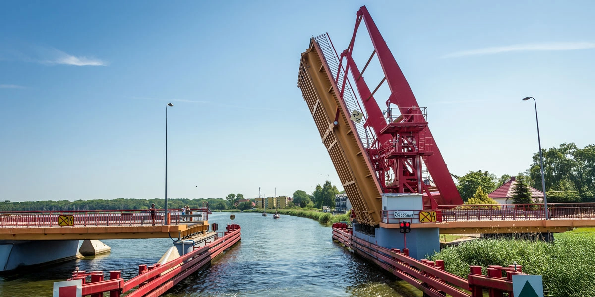 Geöffnete Zugbrücke über die Dziwna in Dziwnów mit roter Stahlkonstruktion und Kanalblick.