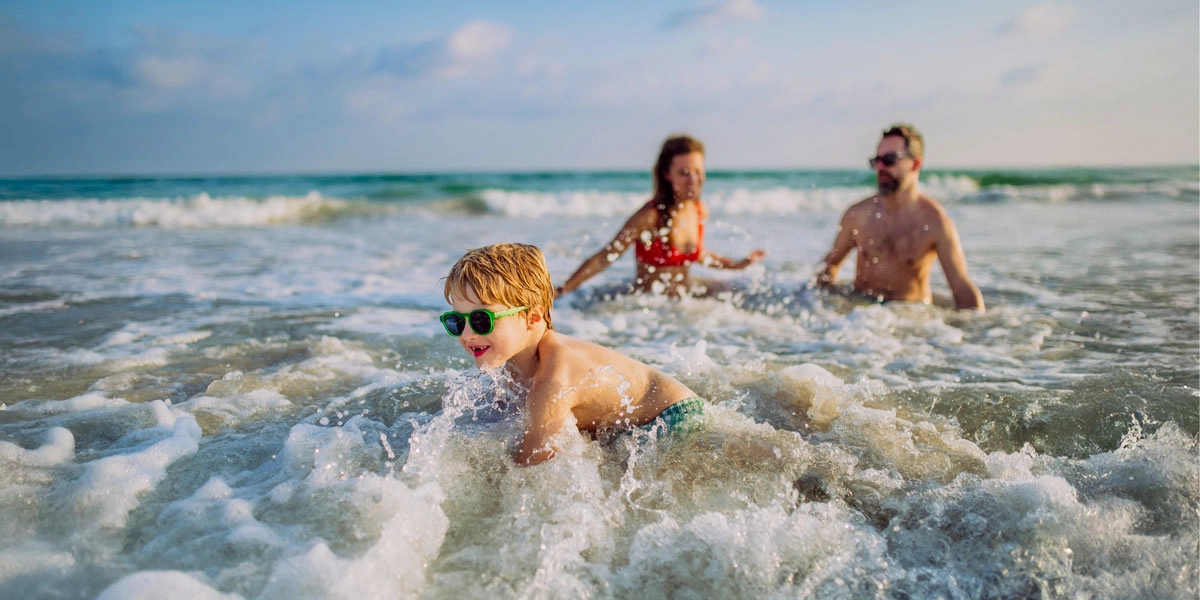 Familie mit Kind badet und spielt in den Wellen der Ostsee bei Misdroy an einem sonnigen Sommertag.