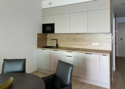 Moderne Küchenzeile im Ferienappartement mit hellen Schränken, Holzarbeitsplatte, Spüle und Küchengeräten.