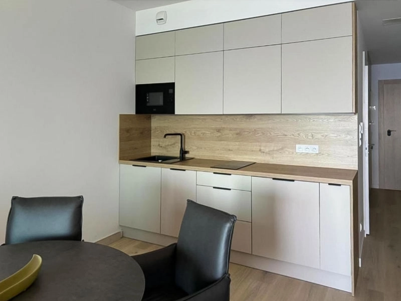Moderne Küchenzeile im Ferienappartement mit hellen Schränken, Holzarbeitsplatte, Spüle und Küchengeräten.