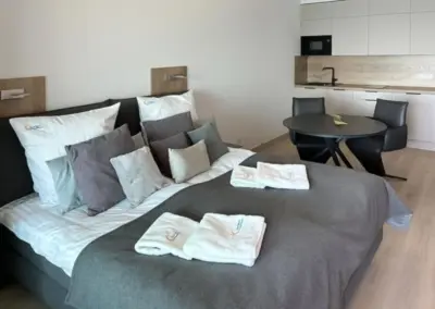 Wohn- und Schlafbereich im Appartement Misdroy mit Doppelbett, frischer Bettwäsche und offener Küchenzeile.