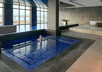 Innenpool im Wellnessbereich der Appartementanlage mit Panoramafenstern und Blick auf Ostsee und Seebrücke.