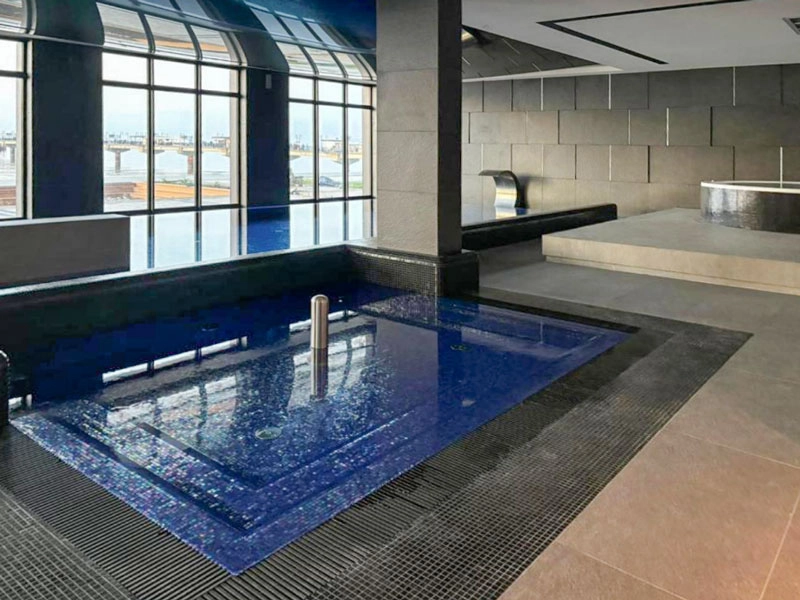 Innenpool im Wellnessbereich der Appartementanlage mit Panoramafenstern und Blick auf Ostsee und Seebrücke.