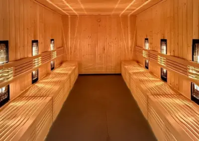 Sauna im Wellnessbereich der Appartementanlage Misdroy mit Holzbänken, warmer Beleuchtung und ruhiger Atmosphäre.
