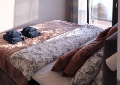 Gemütliches Schlafzimmer im Ferienappartement Dziwnów mit Doppelbett, Tageslicht und Zugang zum Balkon.