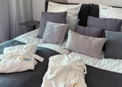 Gemütliches Schlafzimmer im Ferienappartement in Misdroy mit Doppelbett, Kissenarrangement und Bademänteln.