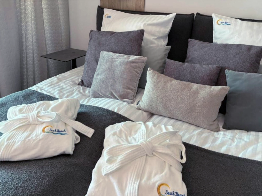 Gemütliches Schlafzimmer im Ferienappartement in Misdroy mit Doppelbett, Kissenarrangement und Bademänteln.