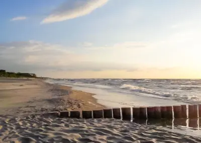Traumhaft schöner Sandstrand in Dziwnów an der Ostsee mit Wellen und weiter Küstenlinie bei ruhigem Abendlicht