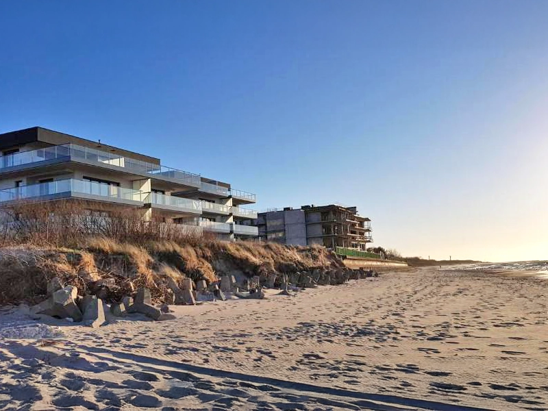 Moderne Ferienanlage in Dziwnów direkt am Sandstrand mit Blick auf die Ostsee bei klarem Himmel.