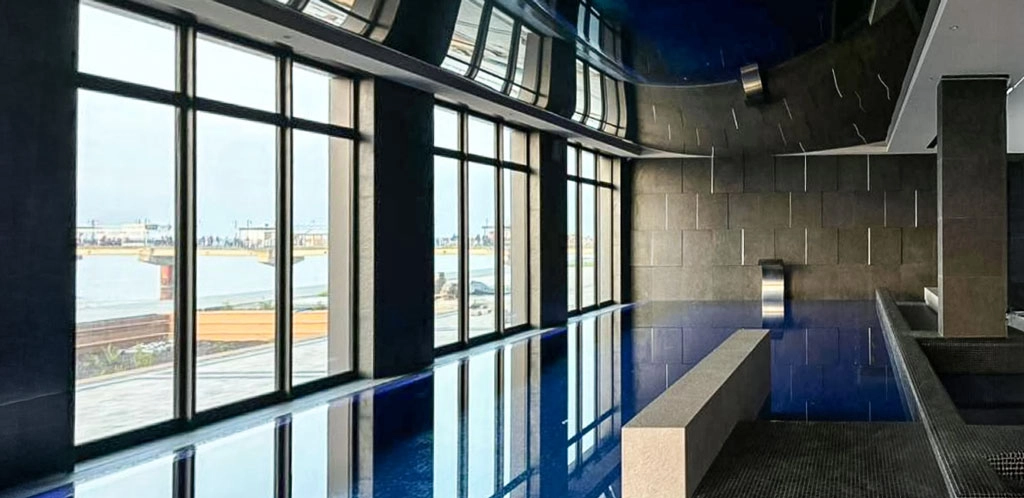 Innenpool im Wellnessbereich der Appartementanlage Misdroy mit Panoramafenstern und Blick nach draußen.