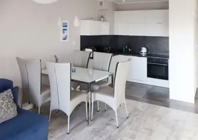 Modern eingerichteter Essbereich mit gedecktem Tisch und Küchenzeile im Ferienappartement in Dziwnów.
