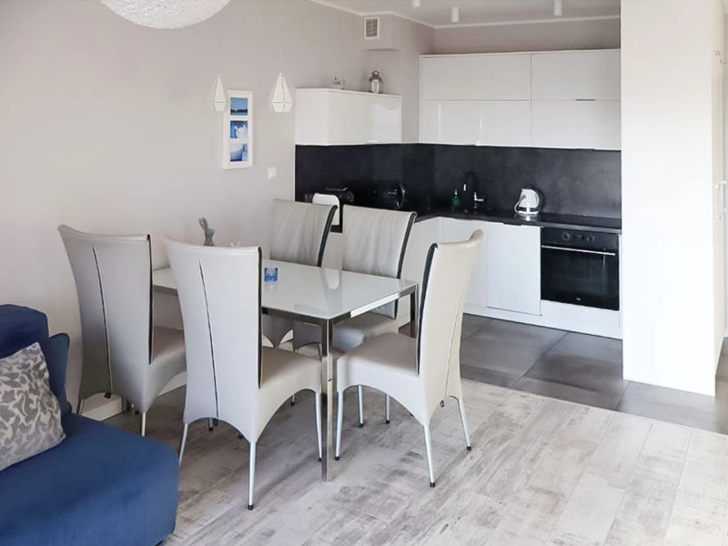 Modern eingerichteter Essbereich mit gedecktem Tisch und Küchenzeile im Ferienappartement in Dziwnów.
